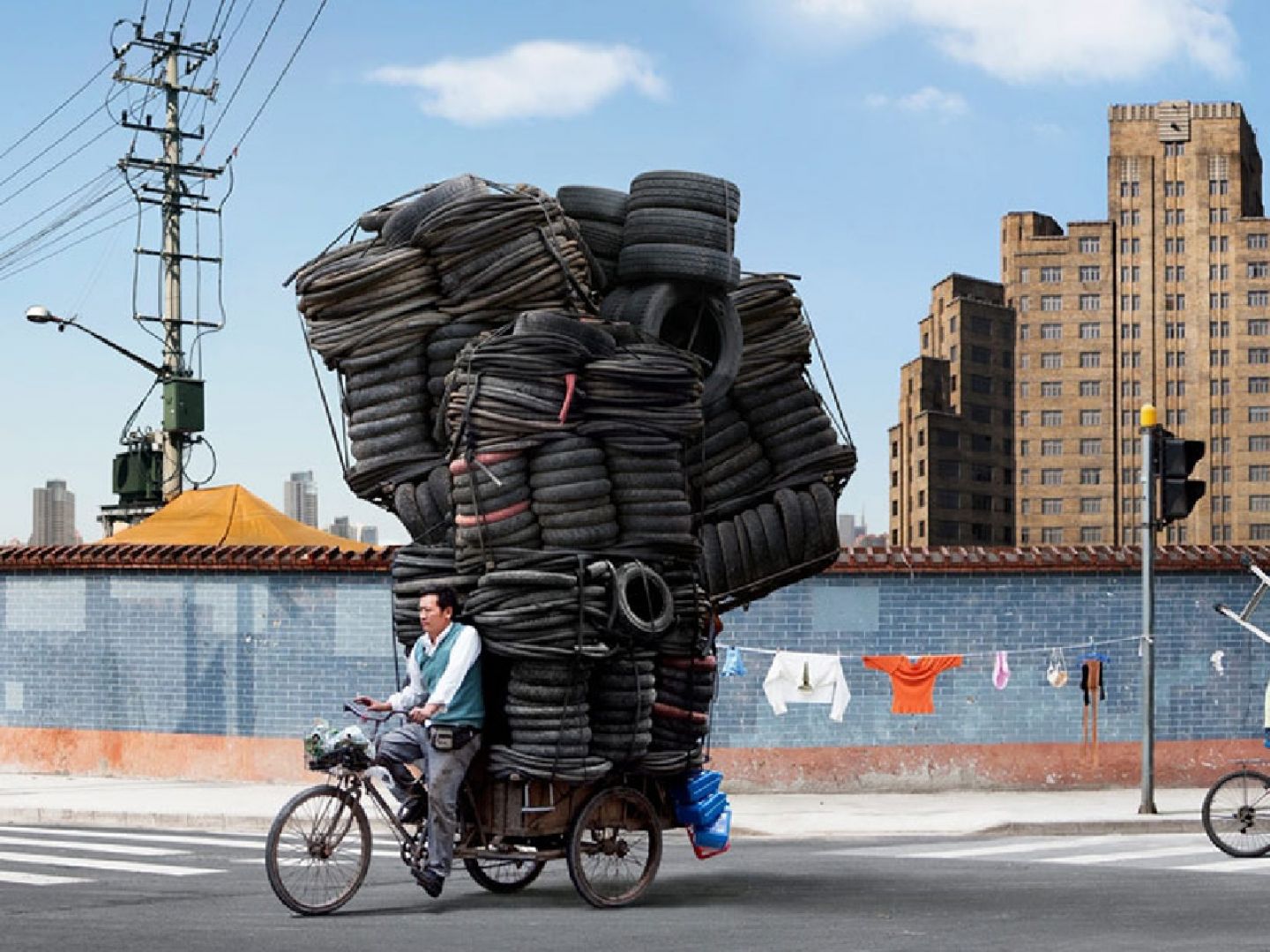 Plakatmotiv von Felix Krull. Auf dem Bild sind ein Mann auf einem Fahrrad mit Türmen von Autoreifen und ein jüngerer Mann ebenfalls am Rad mit einem Leiter auf den Schultern.