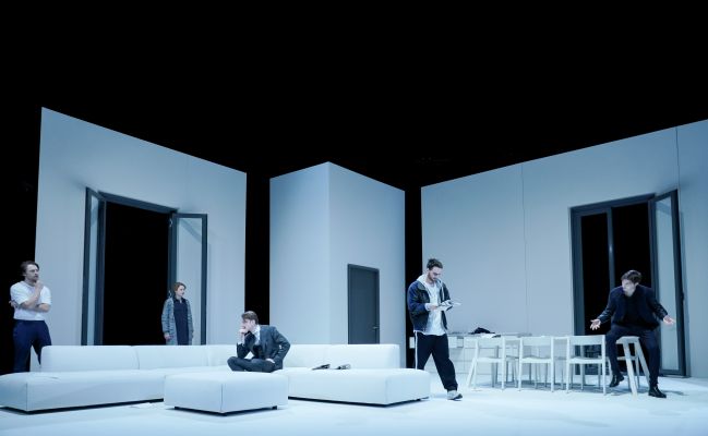 Es ist eine Weitwinkelaufnahme des Bühnenbilds von Bilder von uns zu sehen und das Ensemble steht auf der Bühne.