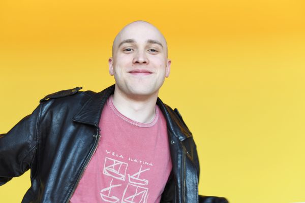 Portrait von Nils Karsten grinsend vor einer gelben Wand