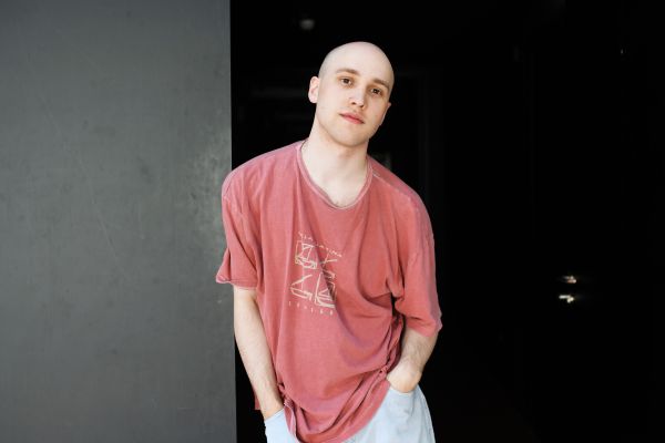 Portrait von Nils Karsten an eine graue Wand angelehnt