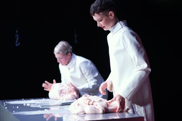 Henriette Nagel, Nina Noé Stehlin (c) Gabriela Neeb Die Rollen von Henriette Nagel und Nina Noé Stehlin stehen nebeneinander an einer Metalltheke. Sie tragen weiße Kittel und bearbeiten eine Masse an Fleisch mit ihren Händen.