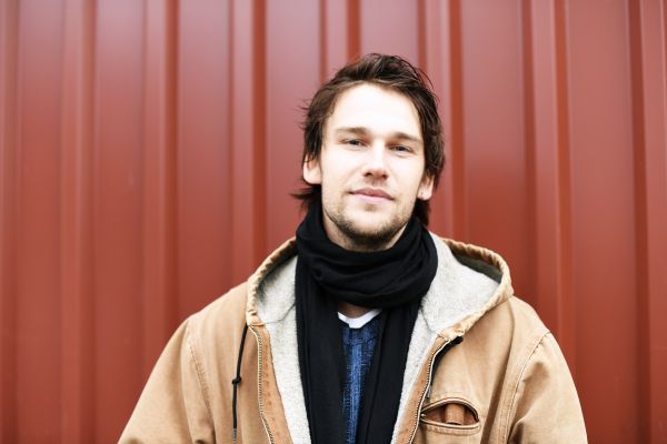 Portrait von Alexandros Koutsoulis vor einer roten Wand