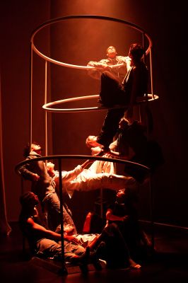 Mehrere Personen befinden sich auf einem Gerüst und werden von oben angestrahlt. oben