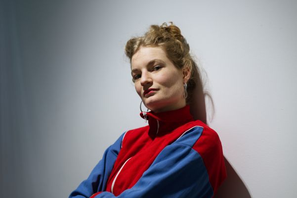 Liv Stapelfeldt (c) Gabriela Neeb Portraitfoto von Liv Stapelfeldt in einer Sportjacke an einer weißen Wand lehnend.