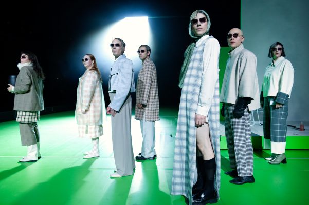 Die Darsteller und Darstellerinnen stehen geordnet neben einander und tragen eine Sonnenbrille.