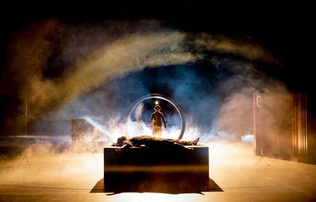 Frankenstein_Nina Noé Stehlin, Cedric Stern (c) Arno Declair Nina Noé Stehlin liegt auf einer Bahre, Cedric Stern geht durch einen Ring auf die Bahre zu, ringsum Nebel.