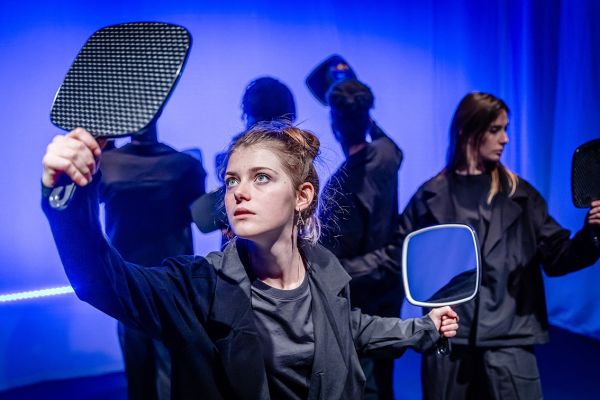 Eine Schauspielerin schaut in den Spiegel, den sie in der Hand hält.