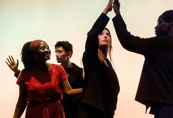 Das Ensemble tanzt auf der Bühne. Zwei Personen berühren sich an den Händen.