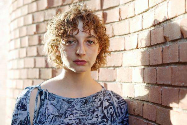 Marlene Markt an einer Ziegelwand, die Sonne im Rücken