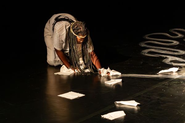 Eine Performerin wischt die Bühne und hinterlässt eine Spur an Dreck.