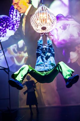 Ein Schauspieler schwingt an einem Kronleuchter.