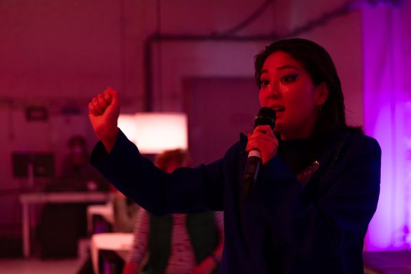 Eine Frau mit dunklen Haaren spricht in ein Mikrofon.