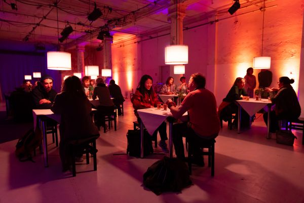 In einem Restaurant sitzen sich an mehreren Tischen jeweils zwei Menschen gegenüber.