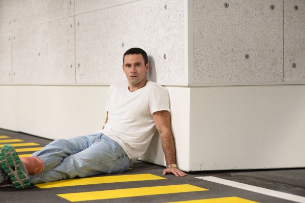 Portraitfoto von einem sitzenden Jonathan Müller in einer Tiefgarage