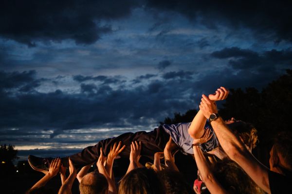 Crowdsurfen eines Mannes. Im Hintergrund sind Gewitterwolken zu sehen.