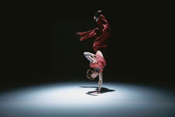 Ein Tänzer macht einen einarmigen Handstand.