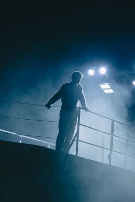 Die Silhouette eines Mannes, der an einer Reling lehnt.