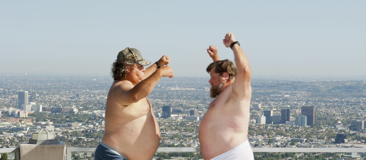 Das Foto zeigt zwei dicke Männer in Unterhose, die tanzen.