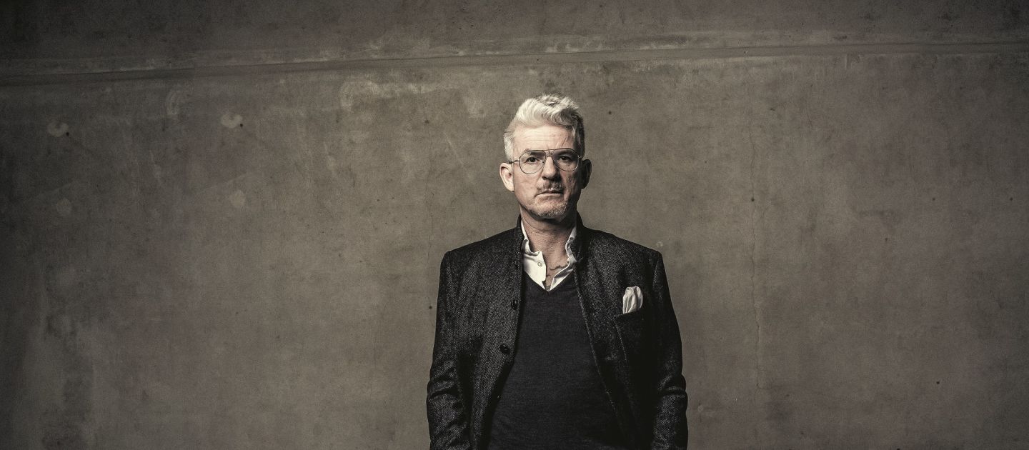 Heinz Strunk (c) Dennis Dirksen Heinz Strunk vor einer grauen Wand