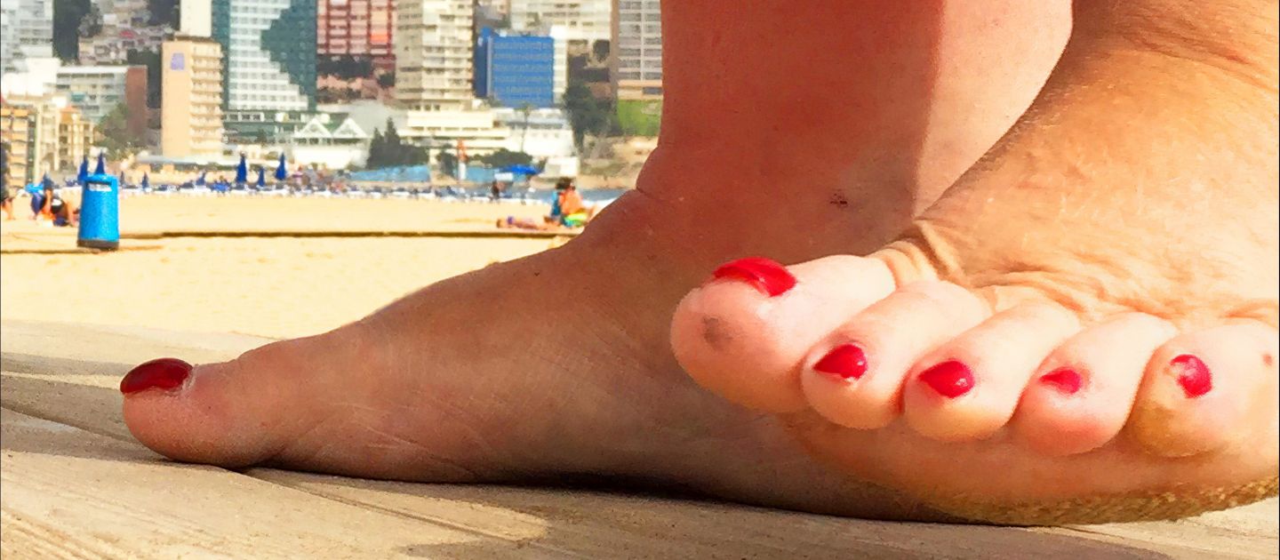 Ein Foto nackter Füße mit roten Nägeln