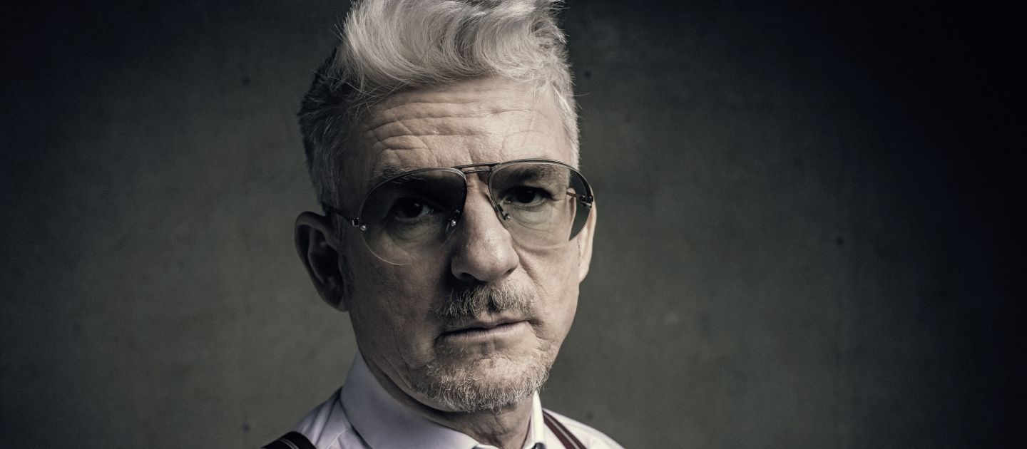 Das Bild zeigt eine Portraitaufnahme von Heinz Strunk. Er trägt eine Pilotenbrille.