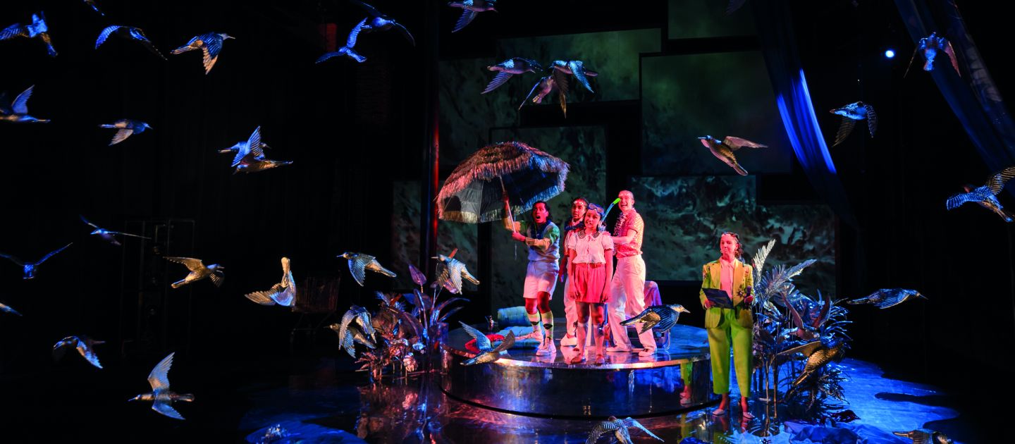 rhapsody (c) Joachim Dette Das Ensemble von "rhapsody" im Bühnenbild: eine Insel umgeben von Vögeln.