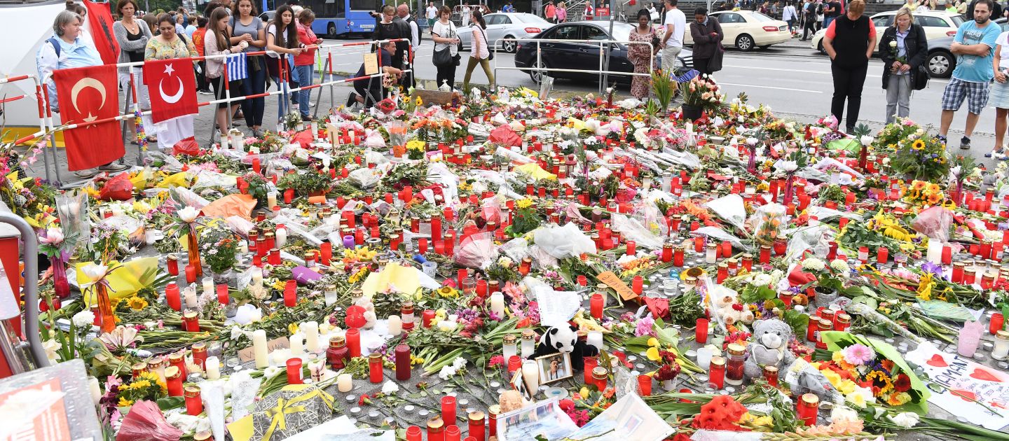 Gedenkort mit niedergelegten Blumen, Bildern, Briefen und Grabkerzen