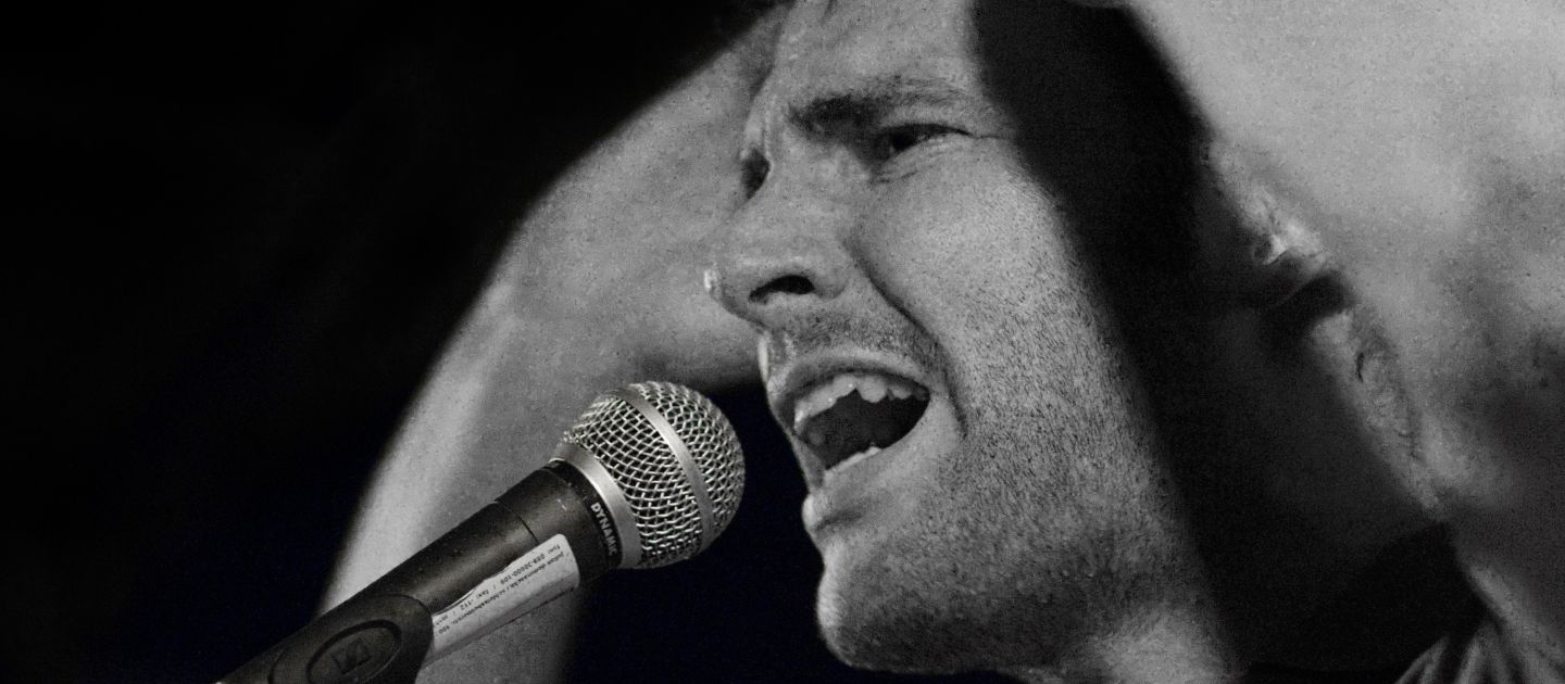 U20 Poetry Slam Ein Slammer spricht in ein Mikro, schwarz-weiße Fotografie