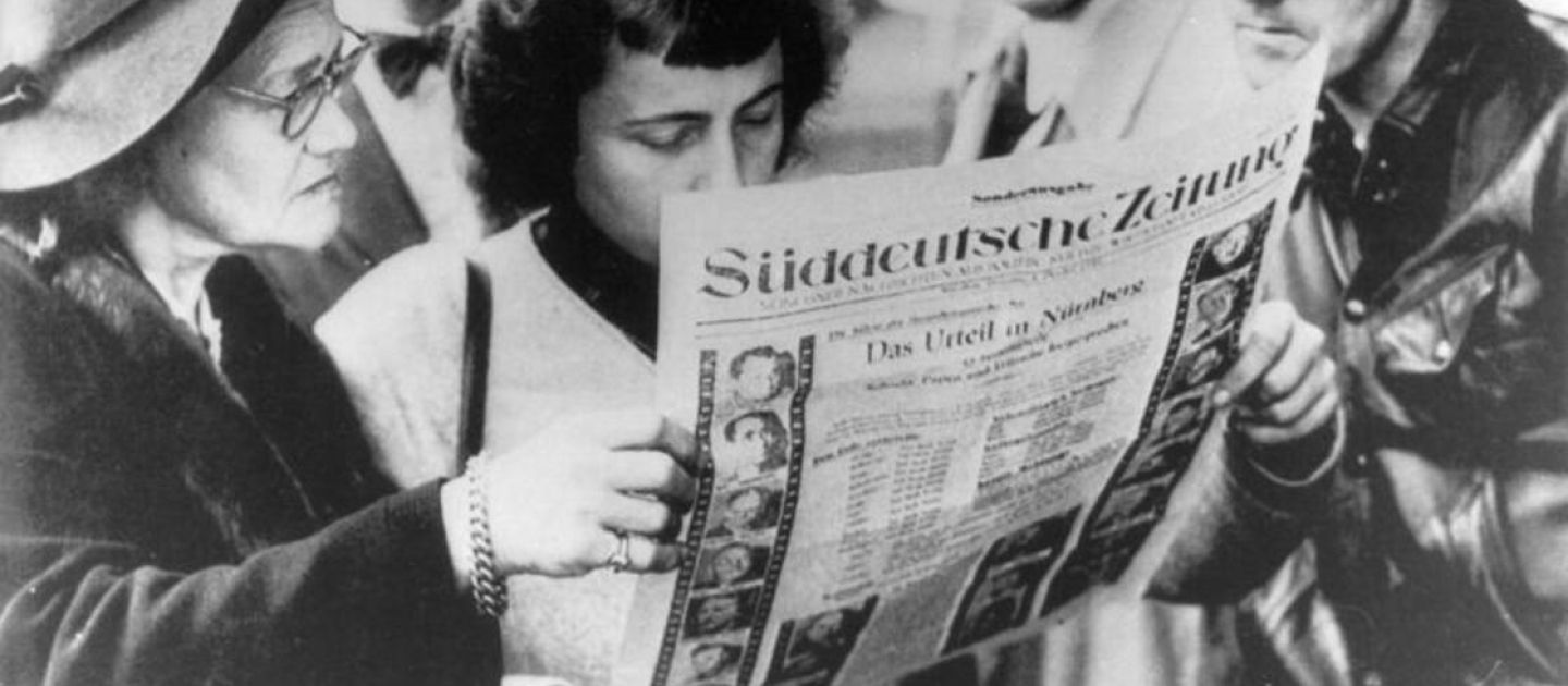 Ein historisches Foto in schwarz-weiß. Eine Gruppe von Menschen lesen die Süddeutsche Zeitung.