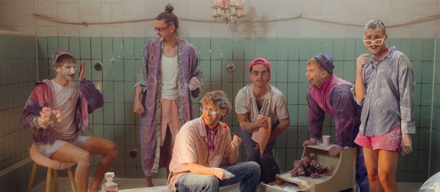 6 Männer stehen vor türkisen Fliesen