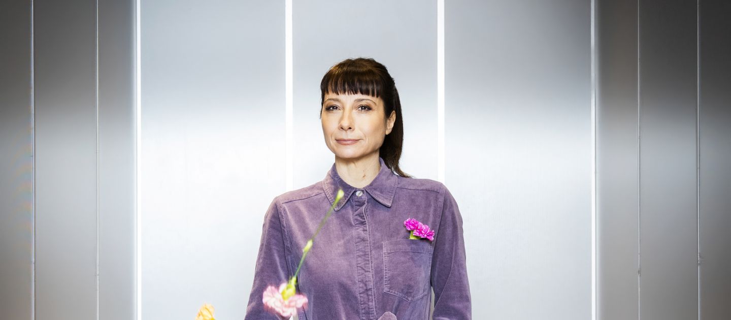 Nina Sonnenberg in einem Aufzug. Blumen fallen von der Decke.