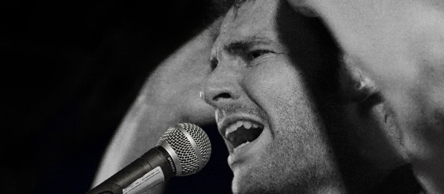 Poetry Slam Ein junger Mann am Mikrophon