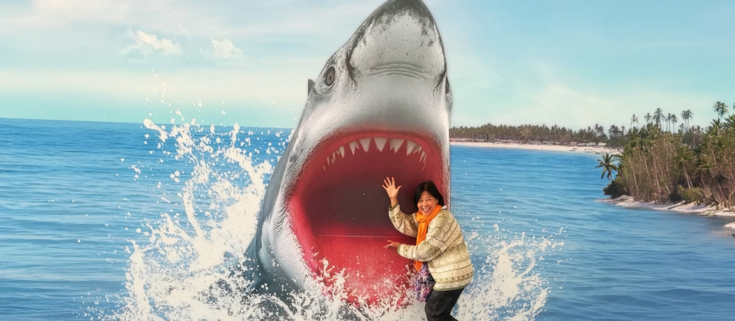 Eine Frau steht vor einer Fotowand mit einem Hai, der aus dem Wasser springt.