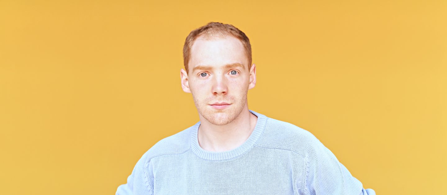 Das Foto zeigt ein Portrait von Jakob Immervoll vor gelben Wand