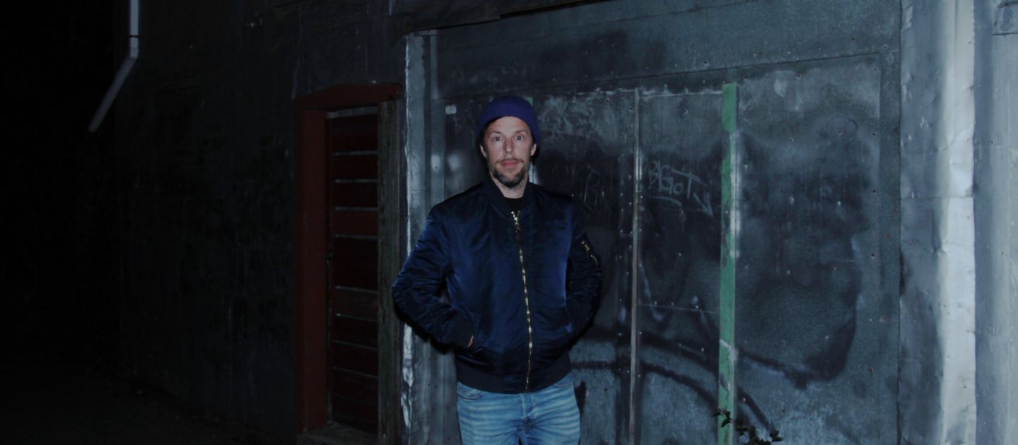 Sebastian Pircher (c) privat Das Bild zeigt Sebastian Pircher frontal in Jeans, dunkelblauer Jacke und Mütze vor einer dunklen Hinergrundkulisse.