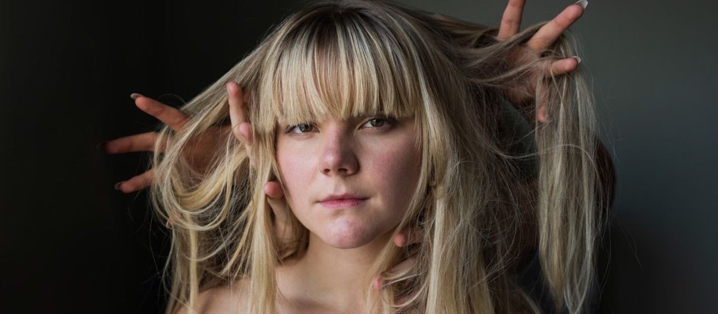 Ein Portraitfoto von Felicia Nilsson. Fremde Hände heben ihre langen Haare.