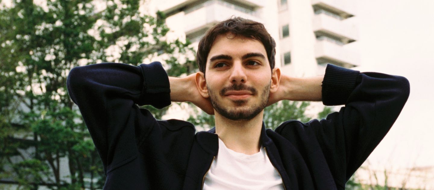 Enes Şahin (c) Leo Rössert Ein Portraitfoto von Enes Şahin vor einem Hochhaus.