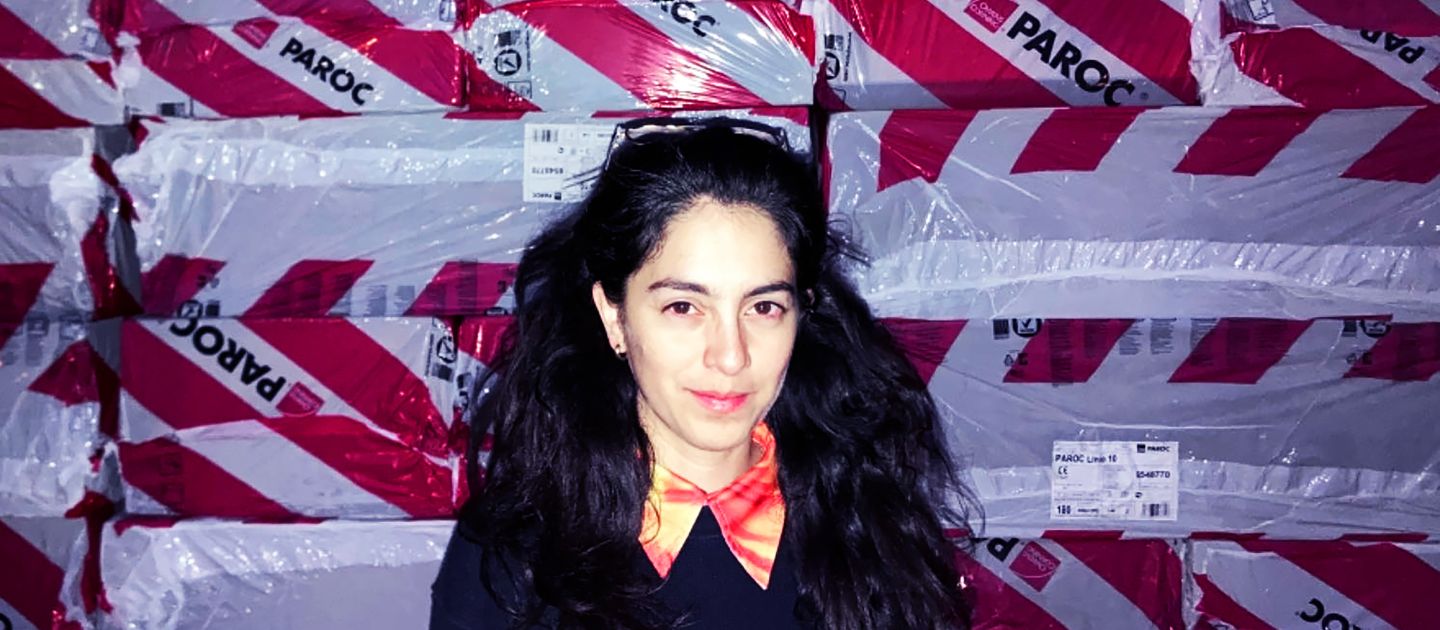 Daniela Zorrozua steht vor Paketen, die in einer rot-weißen Plane verpackt sind.