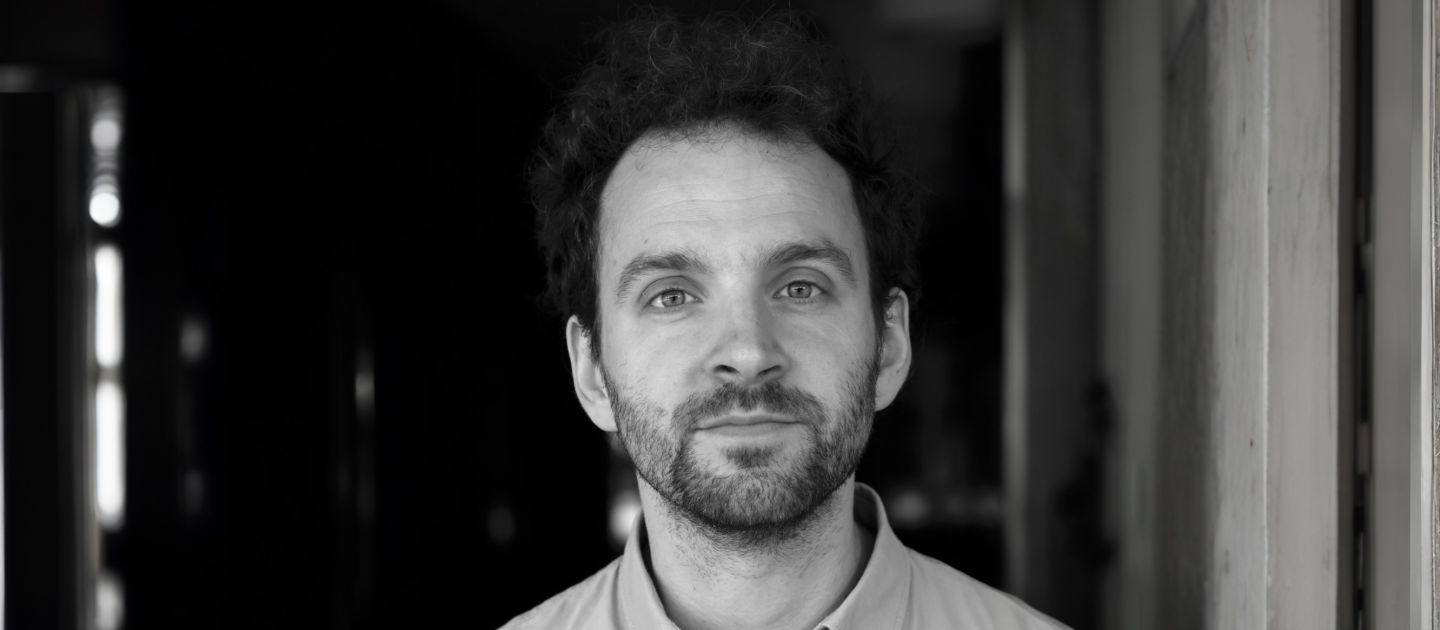 Ben Roessler (c) Thomas Rabsch Ben Roessler steht vor einem Türeingang und blickt in die Kamera.