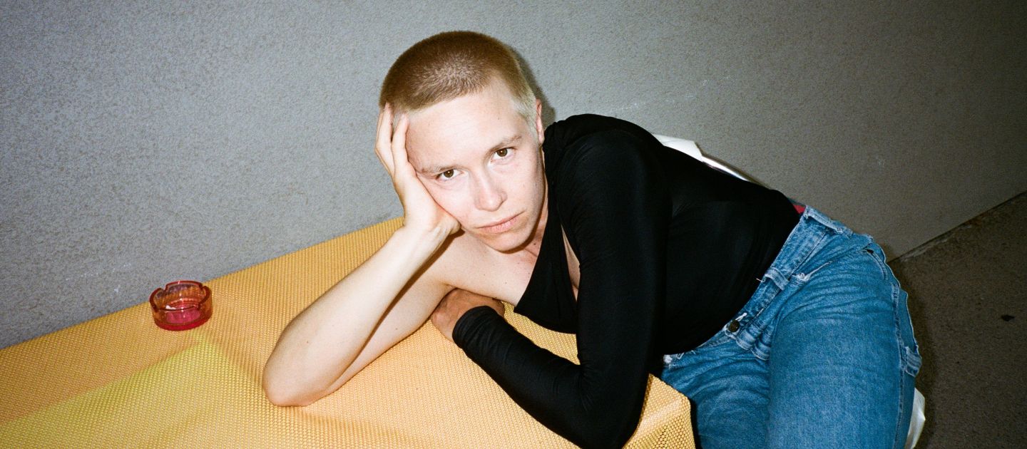 Portraitfoto von Anna Marboe, lehnend an einem kleinen Tisch.