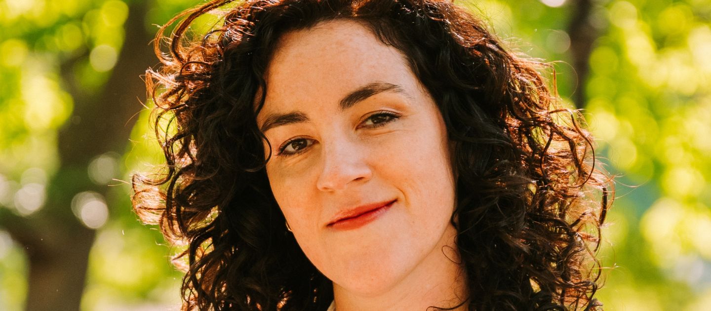 Portraitfoto von Julia Prechsl im Anzug vor grünen Bäumen.