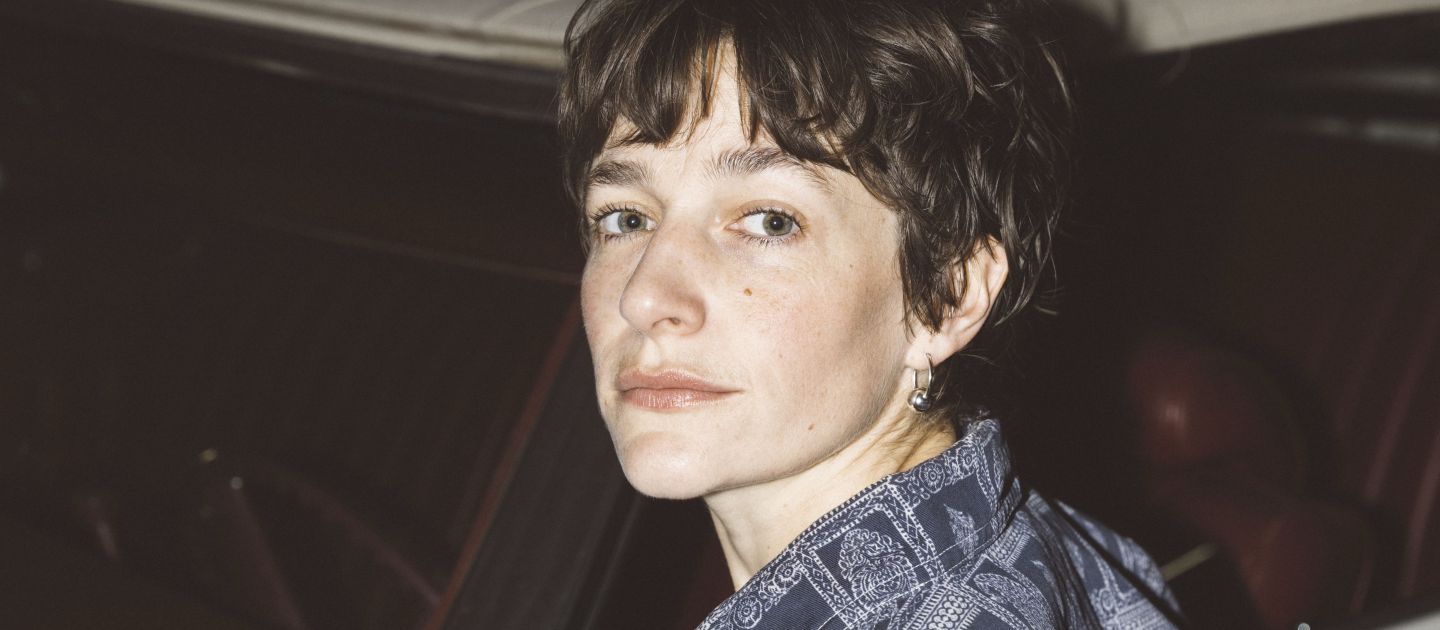 Portraitfoto von Luisa Wandschneider vor einem weißen Auto.
