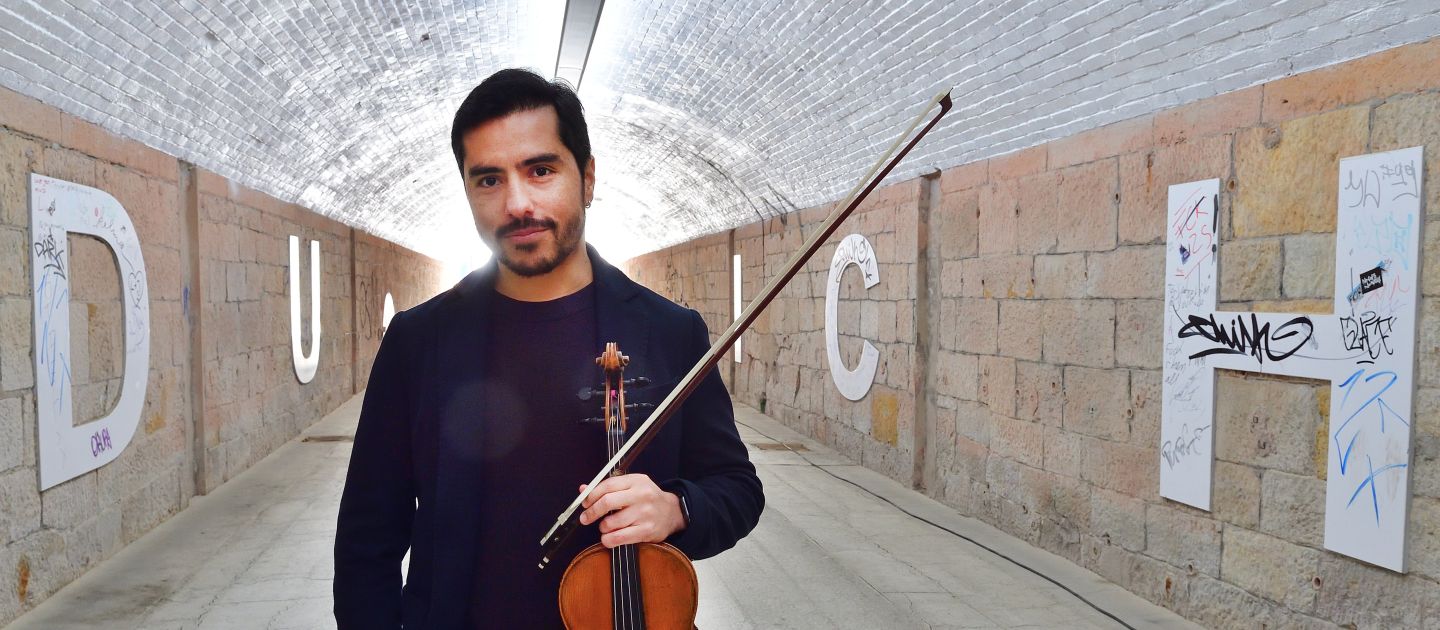 Gustavo Strauß mit Violine in der Hand steht in einem Tunnel.