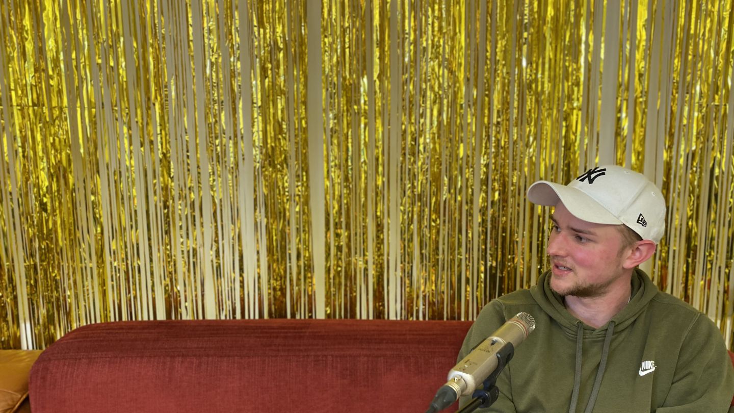 Max Poerting (c) Jenny von Reiche Max Poerting auf einem roten Sofa vor goldenem Lametta