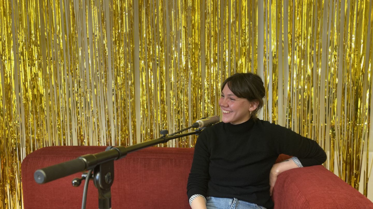 Paula de la Haye sitzt auf einem roten Sofa