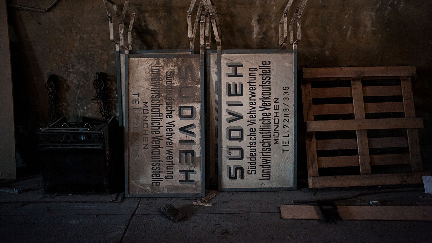 Zwei Schilder mit der Aufschrift Südvieh lehnen neben einer Europalette an der Wand.