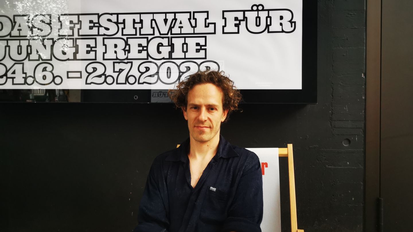 Das Bild zeigt Florian Fischer vor einem Plakat von Radikal jung.