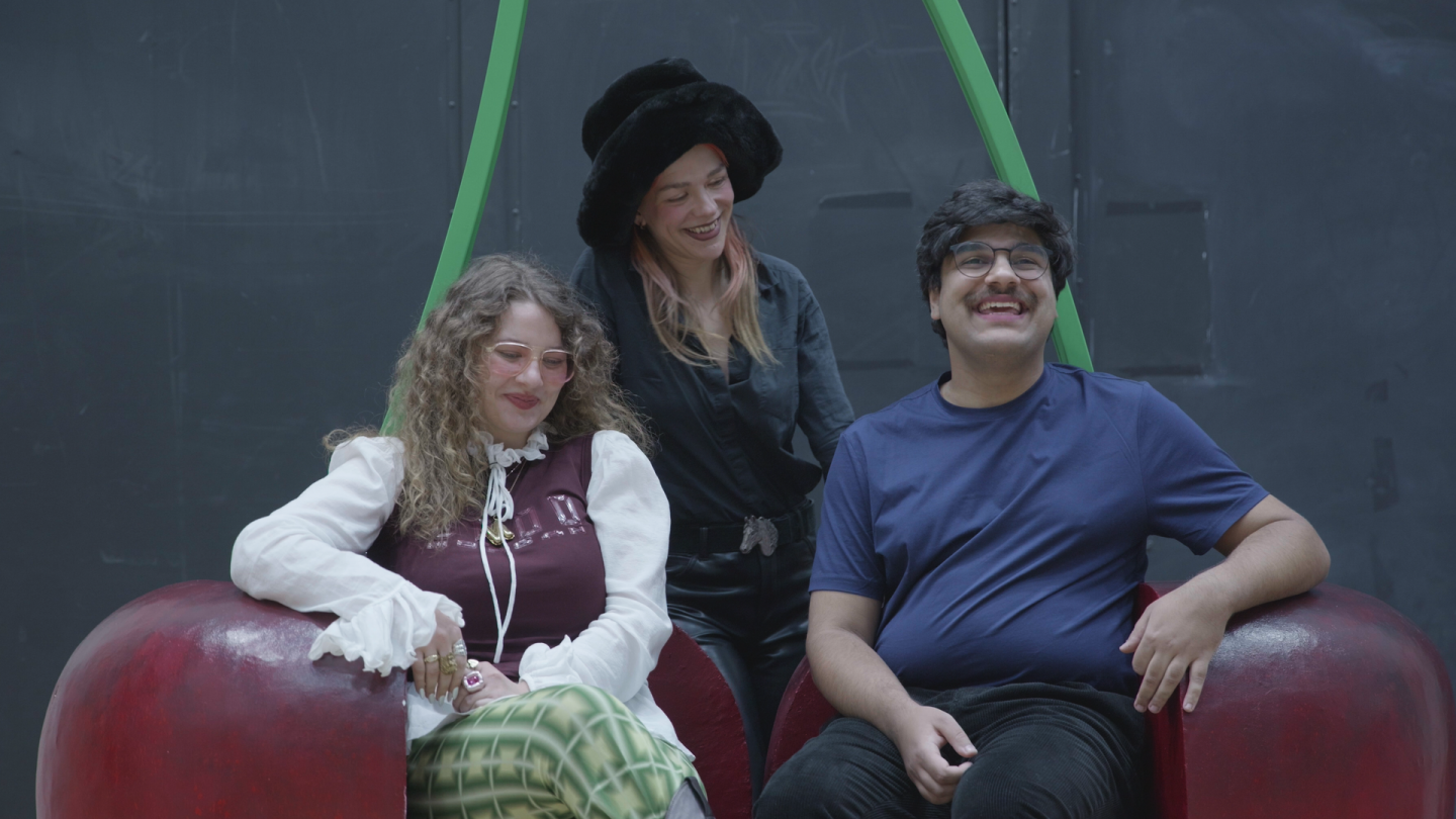 Juli Mahid Carly, Nathalie Schatz und Hanna Rode (c) Katharina Öttl Drei Menschen sitzen auf einer überdimensionierten Kirsche.