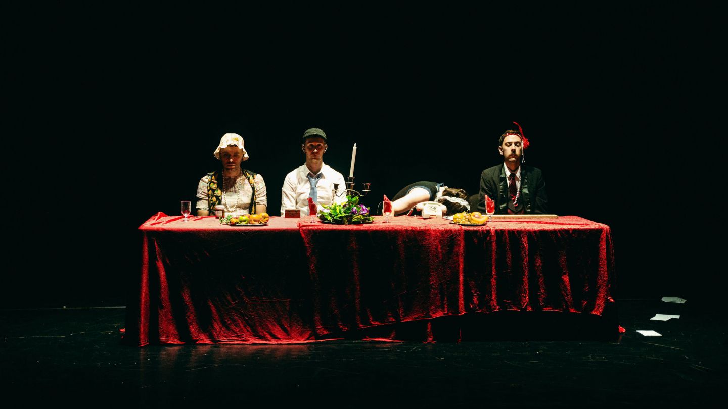 Die vier Künstler von Current Resonance sitzen an einer reich gedeckten tafel.