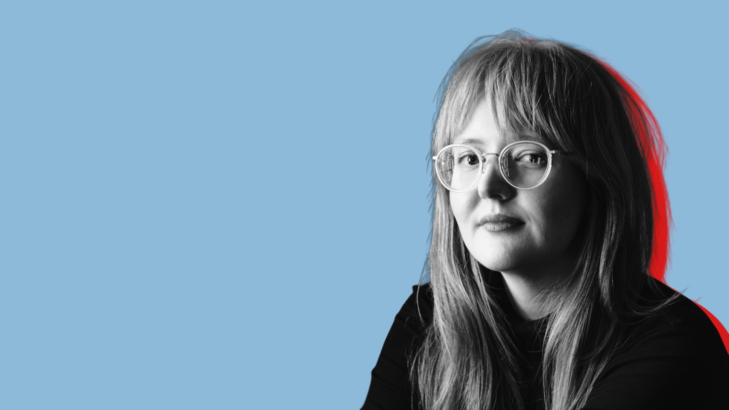 Portraitfoto von Lena Reißner in schwarz-weiß vor blauem Hintergrund.